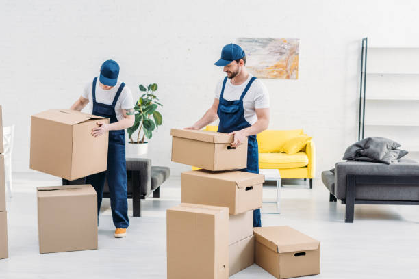 istock two movers in uniform carrying cardboard boxes in modern apartment 1149772786