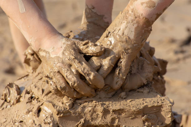 Cute little toddler boy showing mother dirty hands after playing in mud outdoors. Curious child with dirt or soil on palms after discovering world. Hygiene and children healthcare. Washing hands.