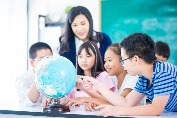 istock Portrait student looking at globe while listening to teacher with magnifying glass 1149783785