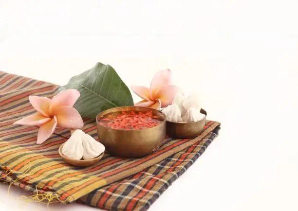 Thai Songkran accessories - bowl of water,flower and clay  on thai fabric  isolated on white