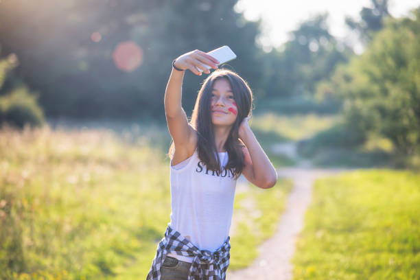 Happy teenage girl making selfie outside.