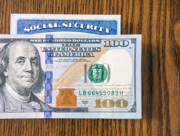 Dollar bills and Social Security Card Looking down on a pile of 100 dollar bills and Social security card social security social security card identity us currency stock pictures, royalty-free photos & images