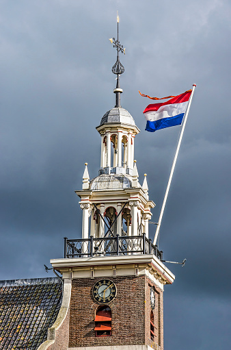 Hardinxveld-Giessendam, The Netherlands, April 27, 2019: The red-white-blue Dutch flag with an orange pennant on the tower of the local church on occasion of King's Day