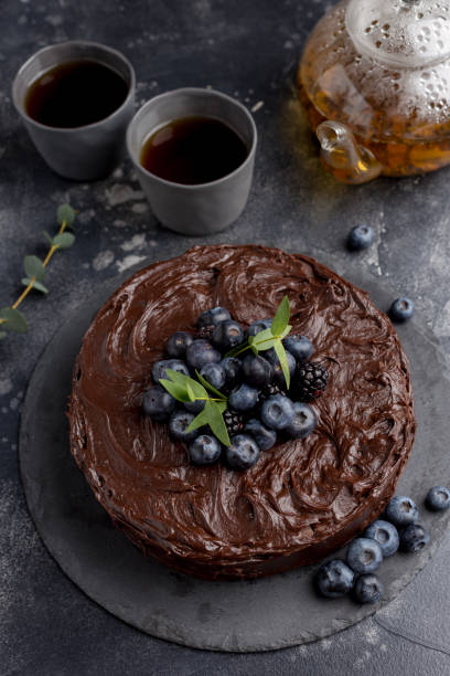 istock Chocolate cake with teapot and cups on dark background 1149810367
