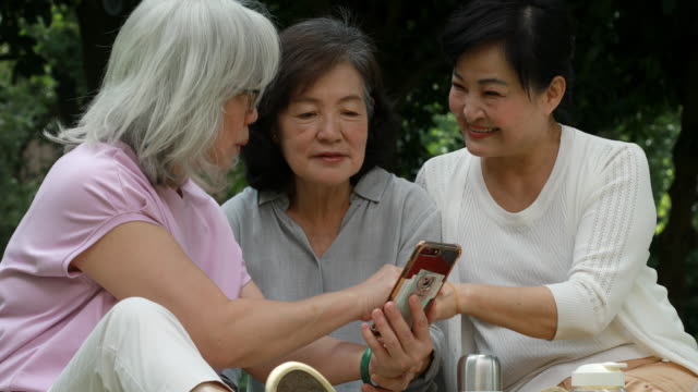 Three Senior Taiwanese Ladies Looking At Smartphone