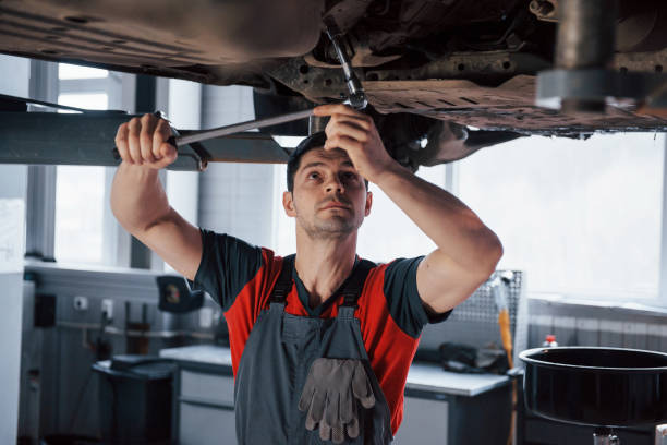 istock Man at the workshop in uniform fixes broken parts of the modern car 1149814412