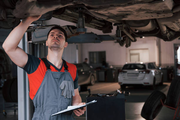 istock Customers behind. Man at the workshop in uniform using notepad for his job for fixing broken car 1149814659