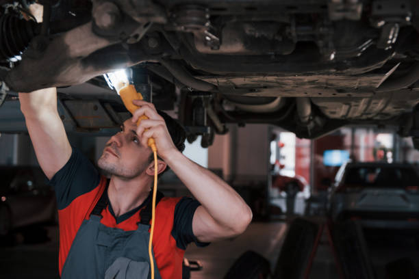 istock Not only strong hands needed but also some good sight. Man at the workshop in uniform fixes broken parts of the modern car 1149814728