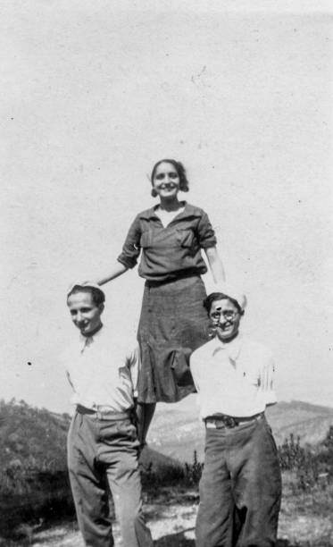 элегантная одетая группа людей, веселясь в небольшом лесу рядом с пляжем. анкона, 1936.италия. - retro revival 1930s style 1930s image women стоковые фото и изображения