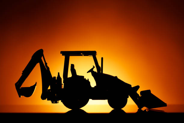 istock backhoe tractor silhouette, orange sunset background 1149819911