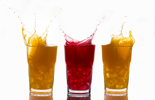 Concept of unique and one of a kind represented with splashes on glasses of orange juice and strawberry juice