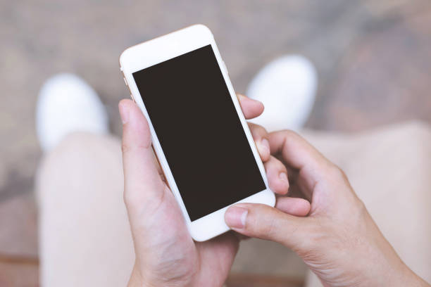 istock Close up of a young man hand holding using mobile smart phone with screen empty cell phone. he sitting chair in public park outdoor. Top view with copy space. 1149822650