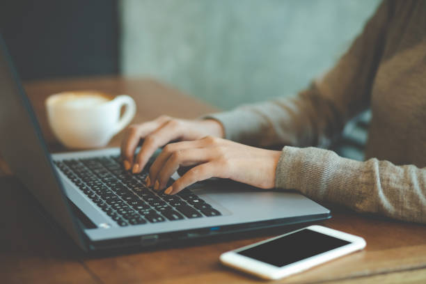 istock business woman freelance sitting using working on his computer notebook laptop and mobile smart phone send work with coffee cup on the table wooden in a cafe coffee shop. working women. 1149823449