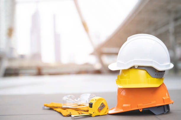 laranja, amarelo, branco rígido de segurança desgaste capacete chapéu no projeto no canteiro de obras de construção em piso de concreto na cidade. capacete para o trabalhador como o coordenador ou o trabalhador. conceito de segurança em primeiro luga - protective workwear hat violence construction - fotografias e filmes do acervo