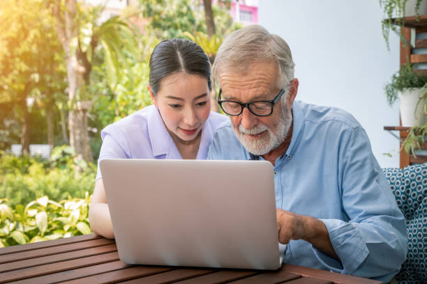 istock Caregiver assist senoir eldery man using notebook laptop computer connect to Internet 1149824914