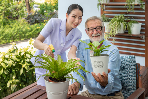 istock Caregiver help assist senior old man eldery puring water and taking care small tree on table looking camera 1149824922