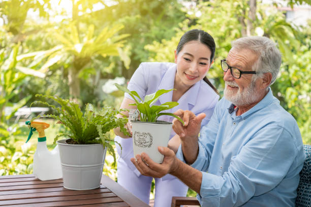 istock Caregiver help assist senior old man eldery puring water and taking care small tree on table 1149824941