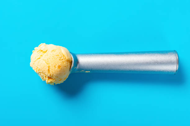 top view spoon with mango flavor ice cream ball on blue background