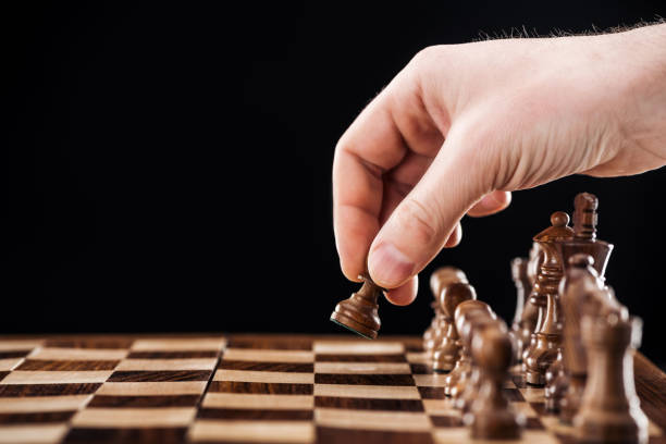 istock partial view of man doing move on wooden chessboard isolated on black 1149832762