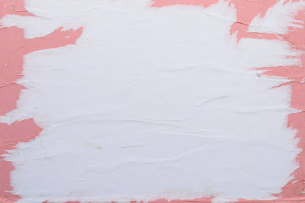 istock White and pink sheets of torn paper pasted on the wall. 1149837025