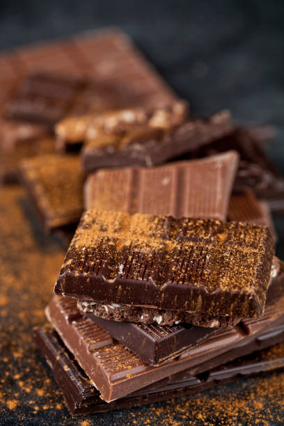 istock Broken chocolate stacked on black background. Chocolate bar pieces heap witn cinnamon powder. 1149838035