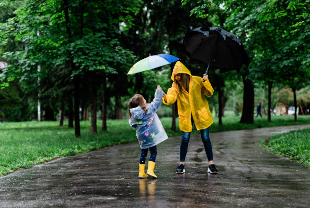 istock Happy mother and daughter holding umbrellas while walking 1149839843