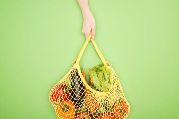 istock partial view of woman holding string bag with whole vegetables on light green 1149839917