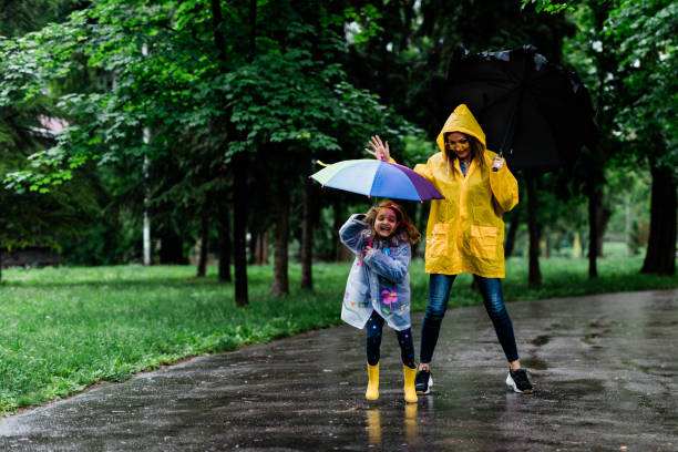istock Happy mother and daughter holding umbrellas while walking 1149840128