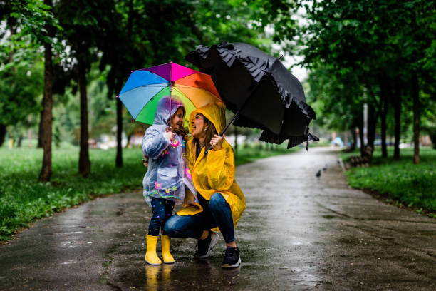istock Happy mother and daughter holding umbrellas while walking 1149840602