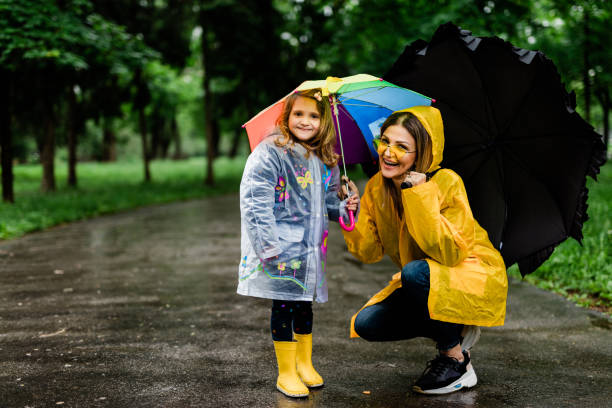 istock Happy mother and daughter holding umbrellas while walking 1149840688