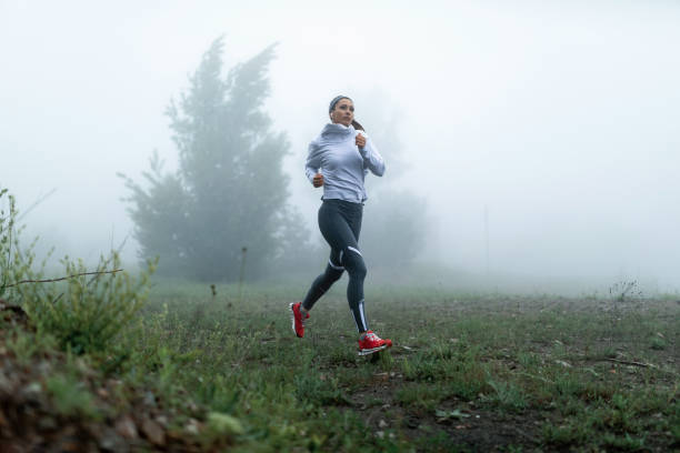 istock Young female jogger running through foggy park. 1149845408