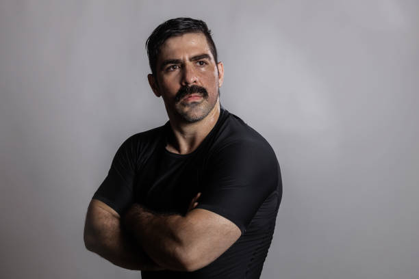 Adult male with moustache with defiant look crossing arms confidently.