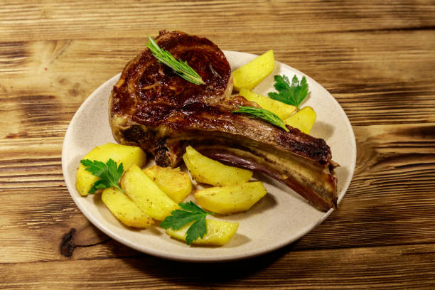 ローストビーフのリブアイステーキ、焼きたてのジャガイモと木のテーブルの上のハーブ - sirloin steak baked potato beef gourmet ストックフォトと画像