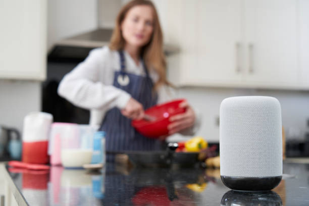 Woman Preparing Meal At Home Asking Digital Assistant Question Woman Preparing Meal At Home Asking Digital Assistant Question virtual assistant stock pictures, royalty-free photos & images