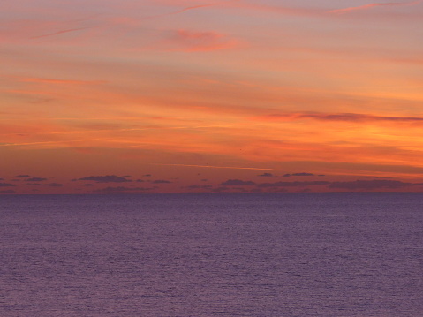 Distant clouds in the evening sunset over a mauve sea off the Brighton coast