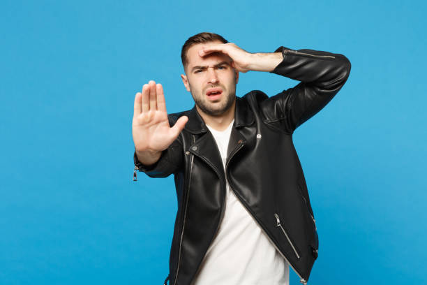Young sad frustrated worried unshaven man in black jacket white t-shirt looking camera isolated on blue wall background studio portrait. People sincere emotions lifestyle concept. Mock up copy space joven triste frustrada preocupado hombre sin afeitar en chaqueta negra camiseta blanca mirando cámara aislada en el retrato del estudio de fondo de pared azul. personas emociones sinceras concepto de estilo de vida. mock up espacio de copia.