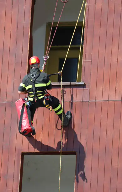 brave climber of the fire brigade during an exercise to access the house from the window lowering himself from above with a safety rope