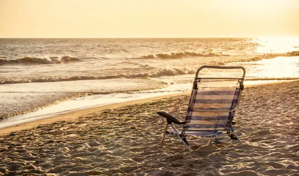 Aluminum striped deckchair at ocean sandy beach with sunset light and vintage tone