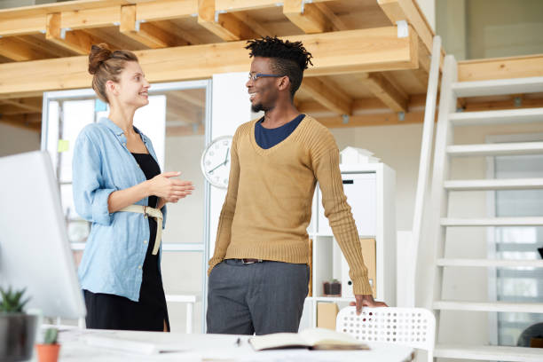 istock Positive young multi-ethnic colleagues talking about new project and discussing its details while standing in modern office 1149873918