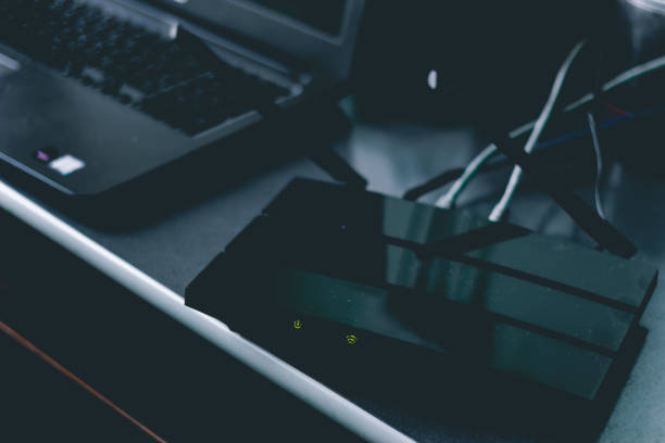 istock Wireless router sitting on a desk next to a laptop 1149876346