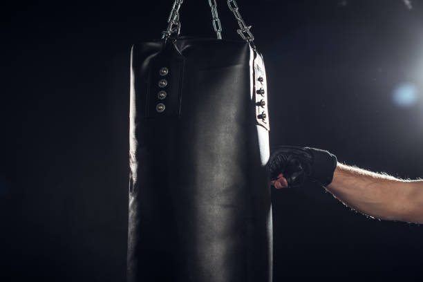 istock Partial view of boxer training with punching bag on black 1149876744