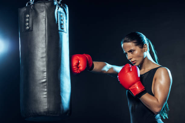 istock Tired boxer in red boxing gloves training with punching bag on black 1149876809