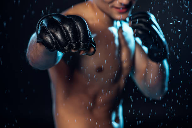 istock Selective focus on boxer in leather gloves standing under water drops on black 1149876821