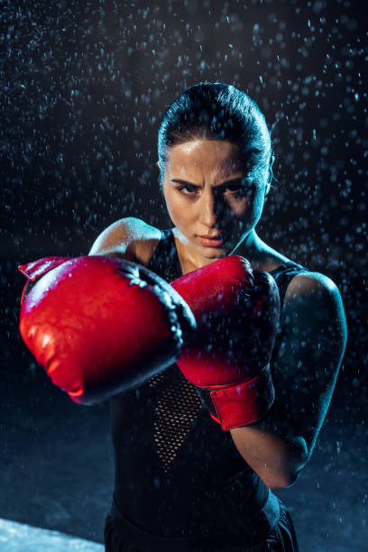 istock Concentrated boxer in red boxing gloves standing under water drops on black 1149876848
