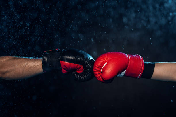 istock Partial view of two boxers in boxing gloves touching hands on black 1149876907