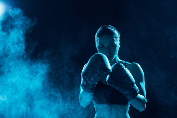 front view of serious boxer in boxing gloves looking at camera - fighting stance imagens e fotografias de stock