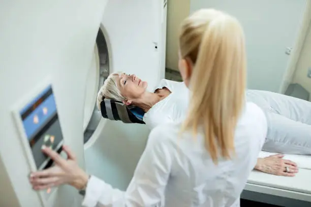 High angle view of mature woman and radiologist during MRI scan examination at clinic.