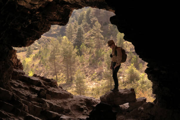 istock ADVENTURER MOUNTAIN MAN WITH HAT AND BACKPACK ENTERING A CAVE OVERLOOKING A BEAUTIFUL VALLEY WITH GREEN TREES IN SUMMER TIME 1149878936