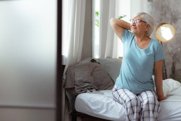 istock Nice-looking woman looking into the window while sitting on bed. 1149885065