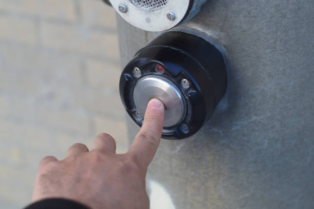 istock pedestrian waiting to cross the street pushing light button 1149891233